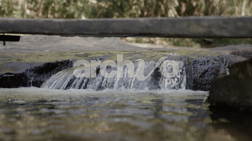 Salto de agua en arroyo con puente de madera en Concepción, plano fijo