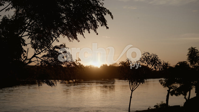 Atardecer sobre el río con siluetas de árboles en Concepción, plano fijo